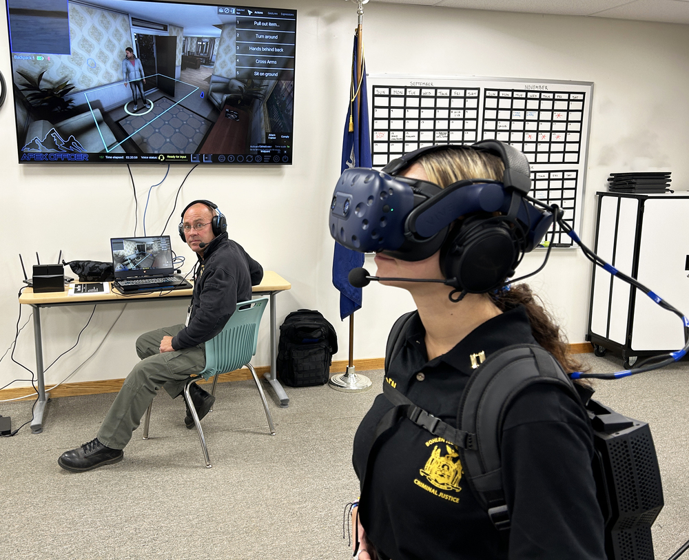 CJ student wears Virtual Reality headgear while instructor looks on 