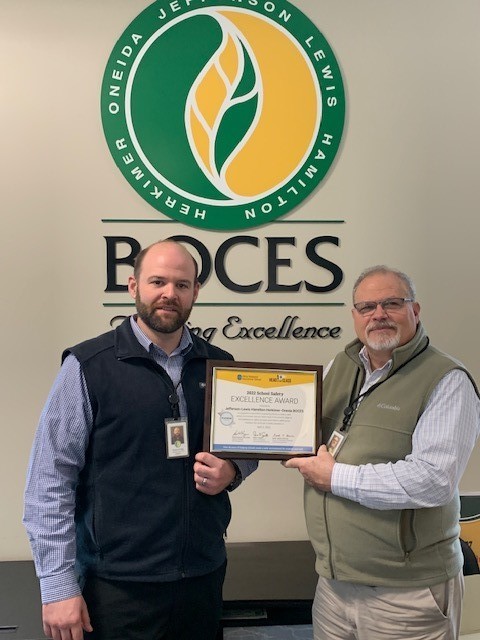 Fritz Hauck and Ray Filley hold award in front of BOCES sign 