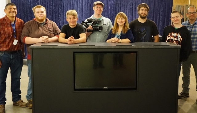 Instructors, students and TV staff stand behind new podium